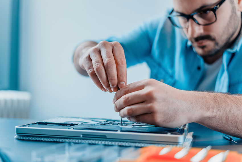 Man in glasses repairing a laptop.